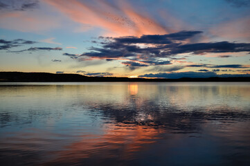 Obraz premium Colourful sunset over the lake Umbukta in Norway. Orange, red, blue colors in Nordic sky reflecting in the water