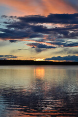 Colourful sunset over the lake in Norway. Orange, red, blue colors in Nordic sky reflecting in the water