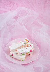 A delicate souffle lies on a plate. A white cake with colored marmalade is lying. A few pieces of sweet delicious pastille.