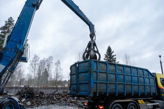 hydraulic grab cleans and tampens metal debris. excavator lifts and throws load with pneumatic paw with claws.