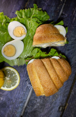 fresh croissant with tuna and egg on a dark background top view.