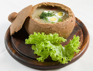 Easter polish sour soup made of rye flour with smoked sausage and eggs served in bread bowl....