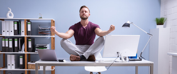 Businessman Meditating Over Desk