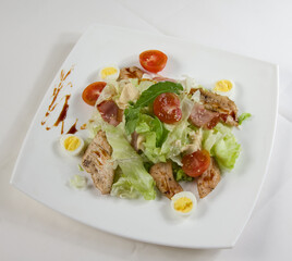 Slices of fried chicken meat with fresh salad on a white plate.