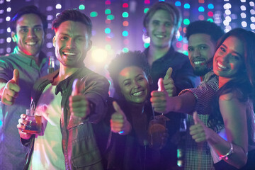 Friday night done right. Portrait of a happy group of friends giving a thumbs up while standing in a nightclub.