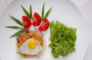 Fototapeta na wymiar Sandwich with meat and egg, fresh green salad, fresh red tomatoes on a white bowl.