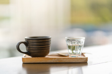 hot americano coffee in black cup served with plain water on wooden table in restaurant and cafe