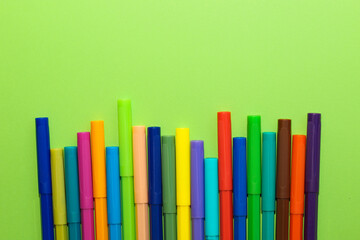 Multi-colored stationery felt-tip pens on a background of multi-colored cardboard paper.