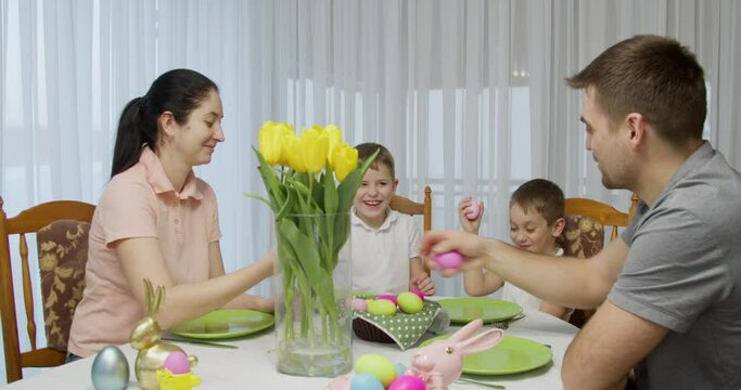family sit at the holiday table, clash colorful eggs. easter dinner