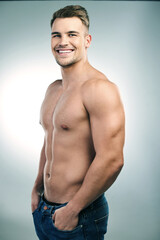 Fototapeta premium Its not magic, these muscles really are all mine. Studio shot of a handsome young man posing shirtless against a grey background.