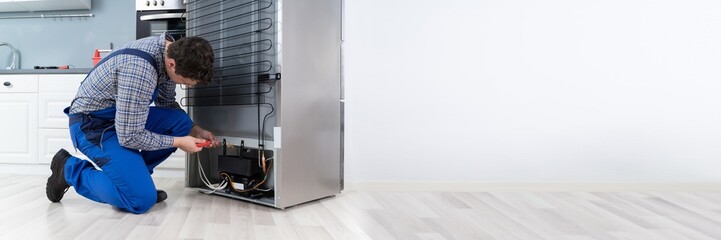 Worker Repairing Refrigerator In House