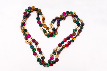Beaded string of colored buttons isolated on white. Heart made from beads.