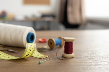 Spool of thread and tailor or sewing accessories with tools at table. Concept of clothes atelier
