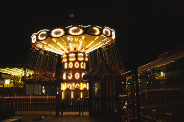 Carousel merry-go-round at night with motion blur on Christmas fair market on holiday season in amusement park in the city