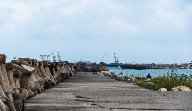 Landscape with fishermen and stabilopod stones near the sea coastline. Mangalia, Romania.