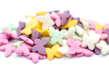A bunch of multi-colored butterflies, sugar sprinkled in pastel colors, lies on a white background.
