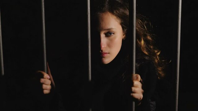 symbol of duress - sad woman clinging the bars looks away thinking