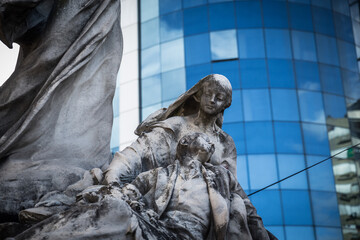 Eine Statue aus Marmor auf dem Friedhog Recoleta, im Hintergrund moderne Architektur