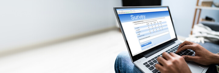 Man Filling Online Survey Form On Laptop - obrazy, fototapety, plakaty