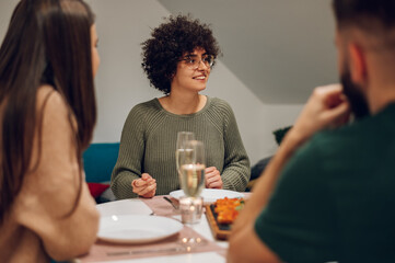 Group of friends enjoying dinner while sitting at the kitchen table together