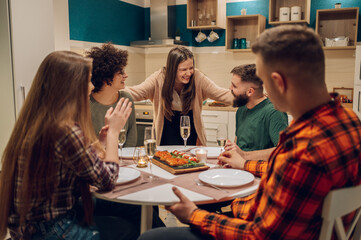 Group of friends enjoying dinner while sitting at the kitchen table together