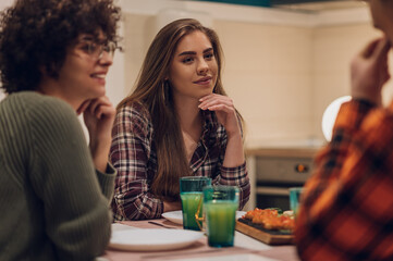 Group of friends enjoying dinner while sitting at the kitchen table together