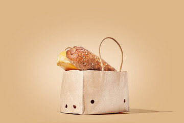 Paper bag full of buns on brown pastel background