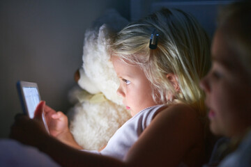 Bedtime has become a lot more interactive. Shot of two little girls using a digital tablet before bedtime.