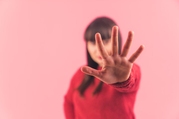 Young dark-haired Caucasian woman showing five fingers to the camera, focus is on the hand pink background isolated studio shot medium closeup copy space . High quality photo