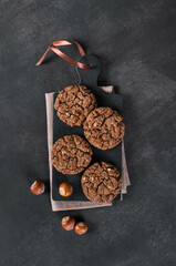 Vegan dessert. Chocolate oatmeal cookies with hazelnuts on a serving board. Dark gray background. Top view