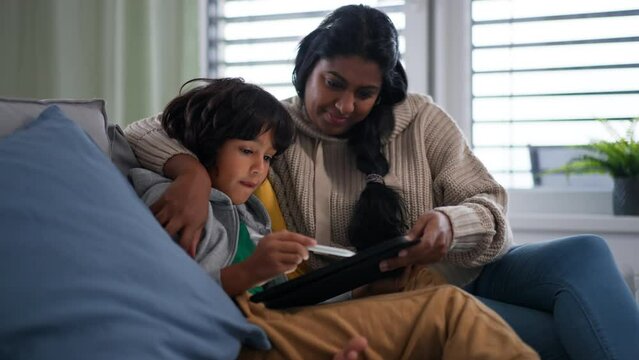 Indian mother using tablet with her little son and having fun at home.