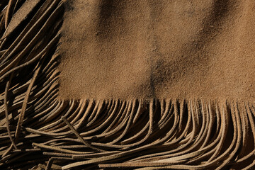 Western industry leather background shows armitas leather with fringe.