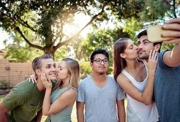 Fifth-wheeling it today. Cropped shot of a young group of friends taking selfies while enjoying a few drinks outside in the summer sun.