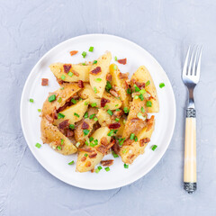 Bacon and onion potato salad dressed with apple cider vinegar and mustard, on plate, square
