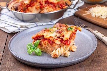 Mac and cheese with meatballs, mozzarella, tomato sauce and basil, on a gray plate, horizontal