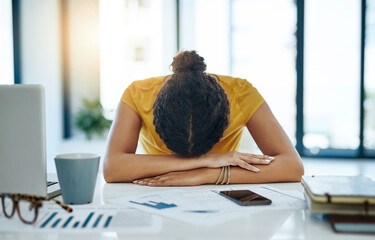 When will this day end. Shot of a young designer with her head down on her office desk.