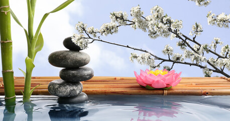 Stack of zen stones and bamboo in water against blue sky