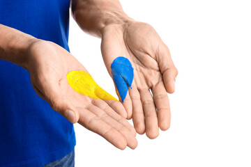 Man with drawn heart in colors of Ukrainian flag on his palms against white background
