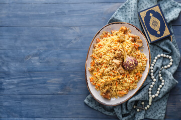 Plate of traditional pilaf with Quran and tasbih on table