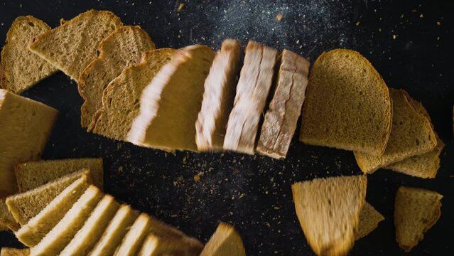 Fresh baked boule, a large round bread, whole and cut into thin delicious slices, isolated on a black background, top close up shot.