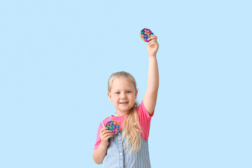 Portrait of happy little girl with multicolored pop it fidget toys on color background