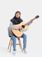 Fototapeta na wymiar Muslim music teacher with guitar on light background