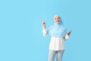 Muslim secretary with calculator pointing at something on color background