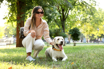 Beautiful woman with cute Labrador in park on summer day