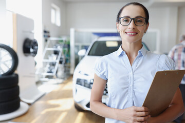 Sales manager holding clipboard in car showroom