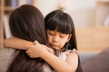 Asian Mum her little daughter hugging sit on sofa smile.Loving family portrait, Mothers Day celebration concept .