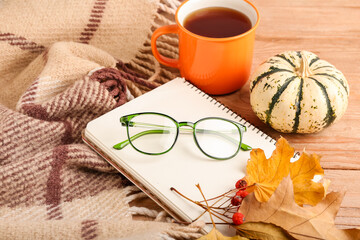 Autumn composition with eyeglasses, notebook and pumpkin on wooden background