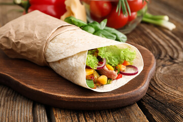 Board of tasty burrito with meat on wooden background
