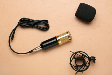 Modern microphone with stand and wire on beige background