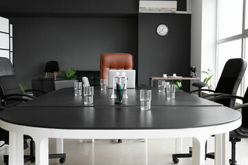 Large table with glasses and bottles of water in conference hall